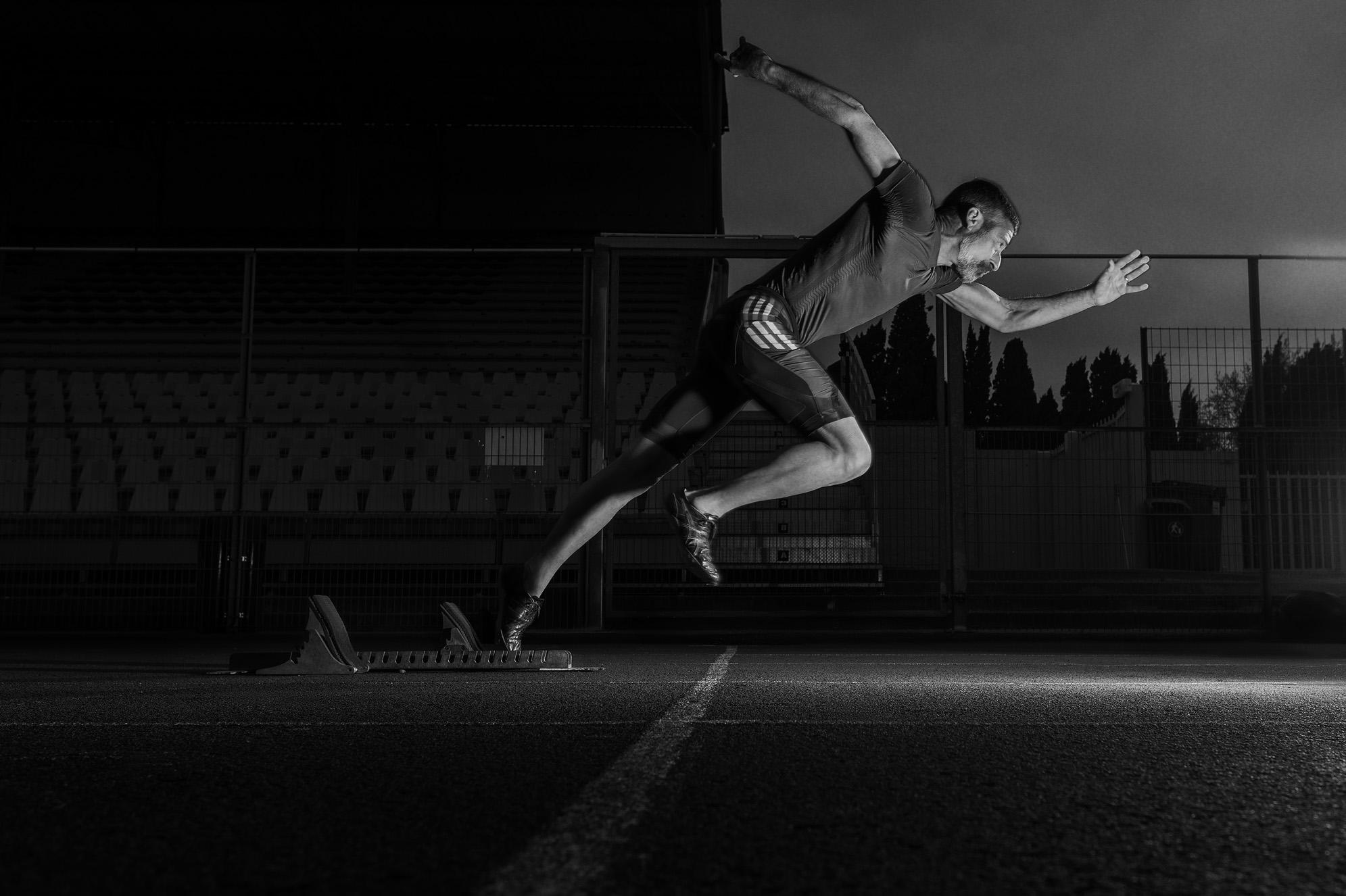 Off the Blocks — David Frey jaillissant des starting-blocks sur une piste de nuit, en noir et blanc