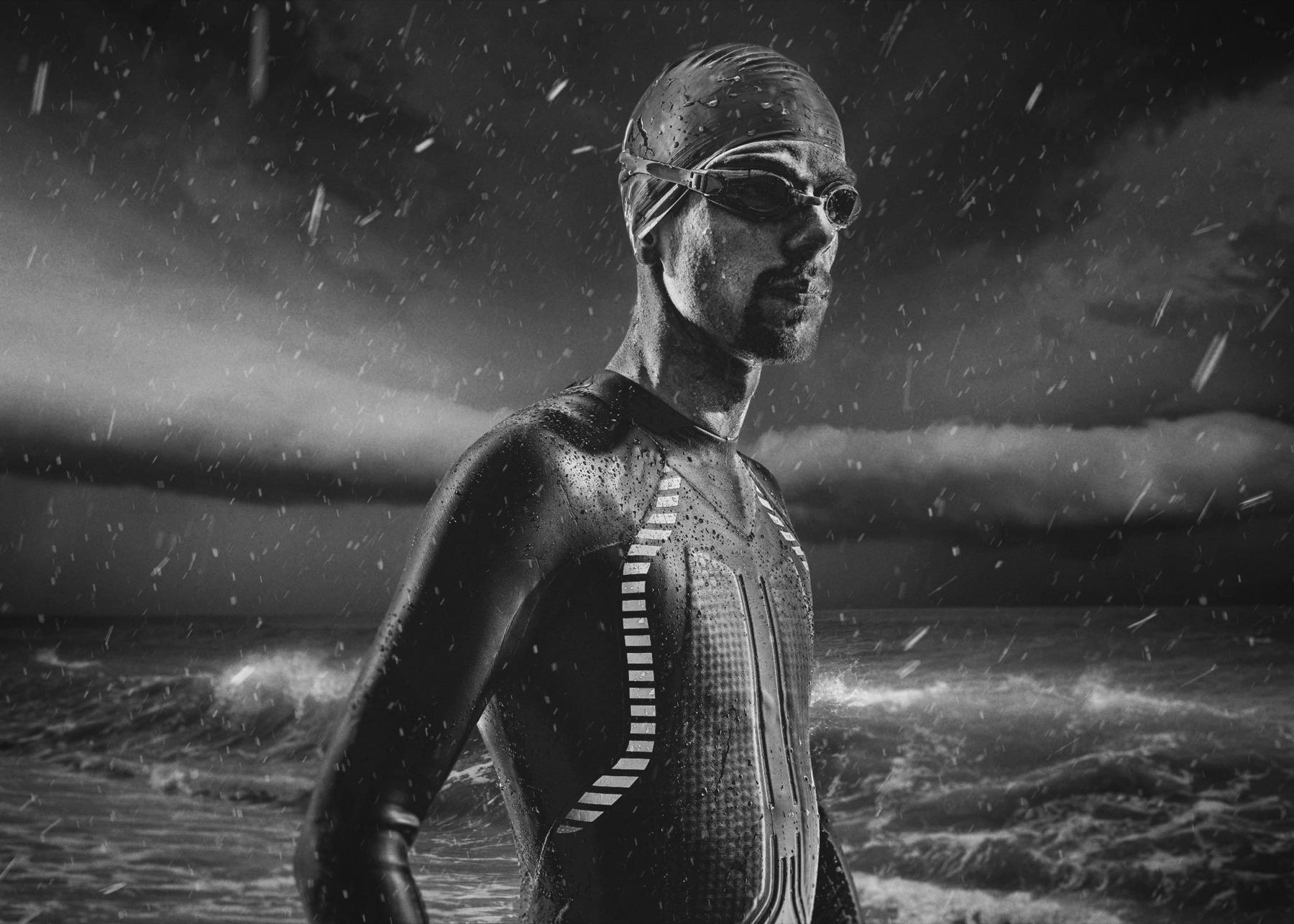 Rough Water — Triathlète en combinaison face à une mer déchaînée sous la pluie, en noir et blanc