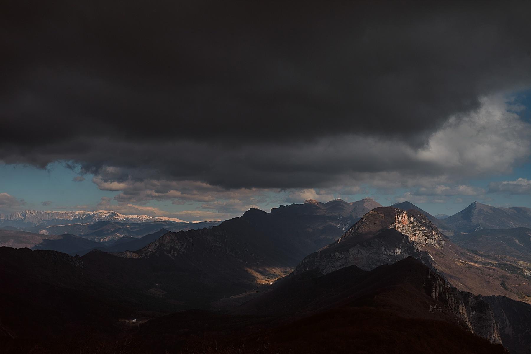 Before the Rain — Chaîne de montagnes sous un ciel d’orage, sommets enneigés au loin