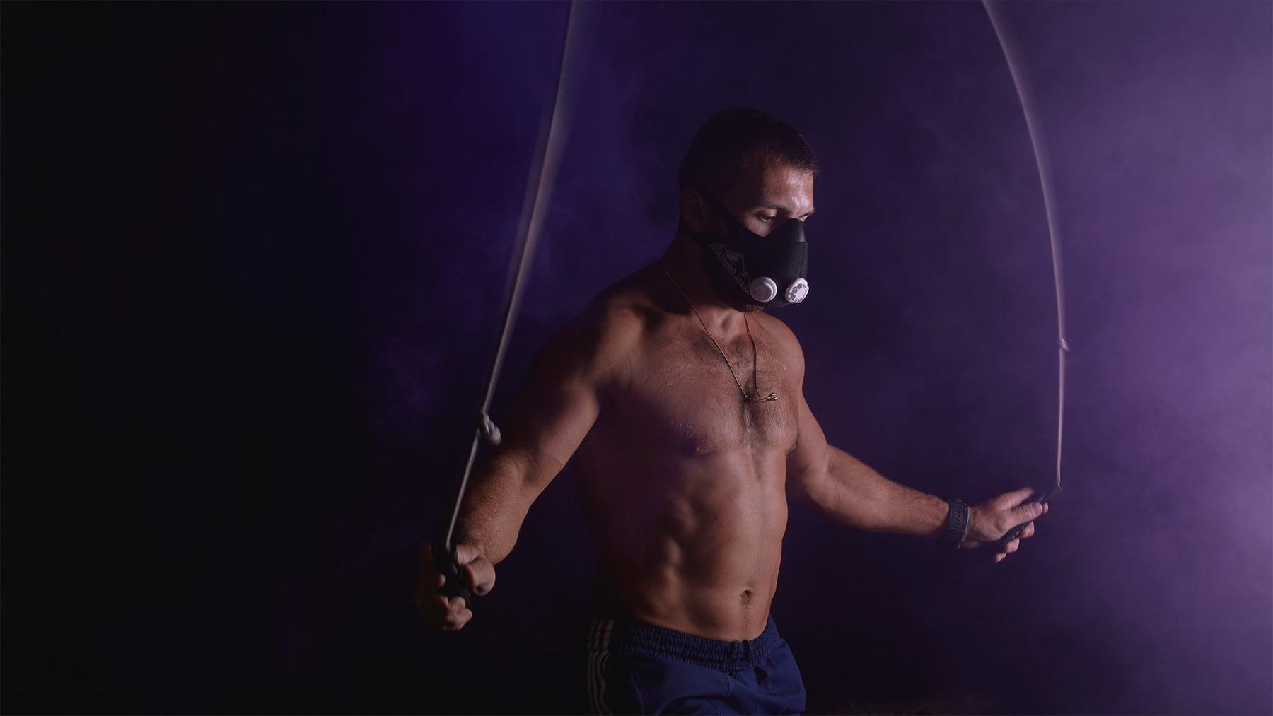 Breath — Homme torse nu portant un masque d’entraînement, sautant à la corde dans une fumée violette